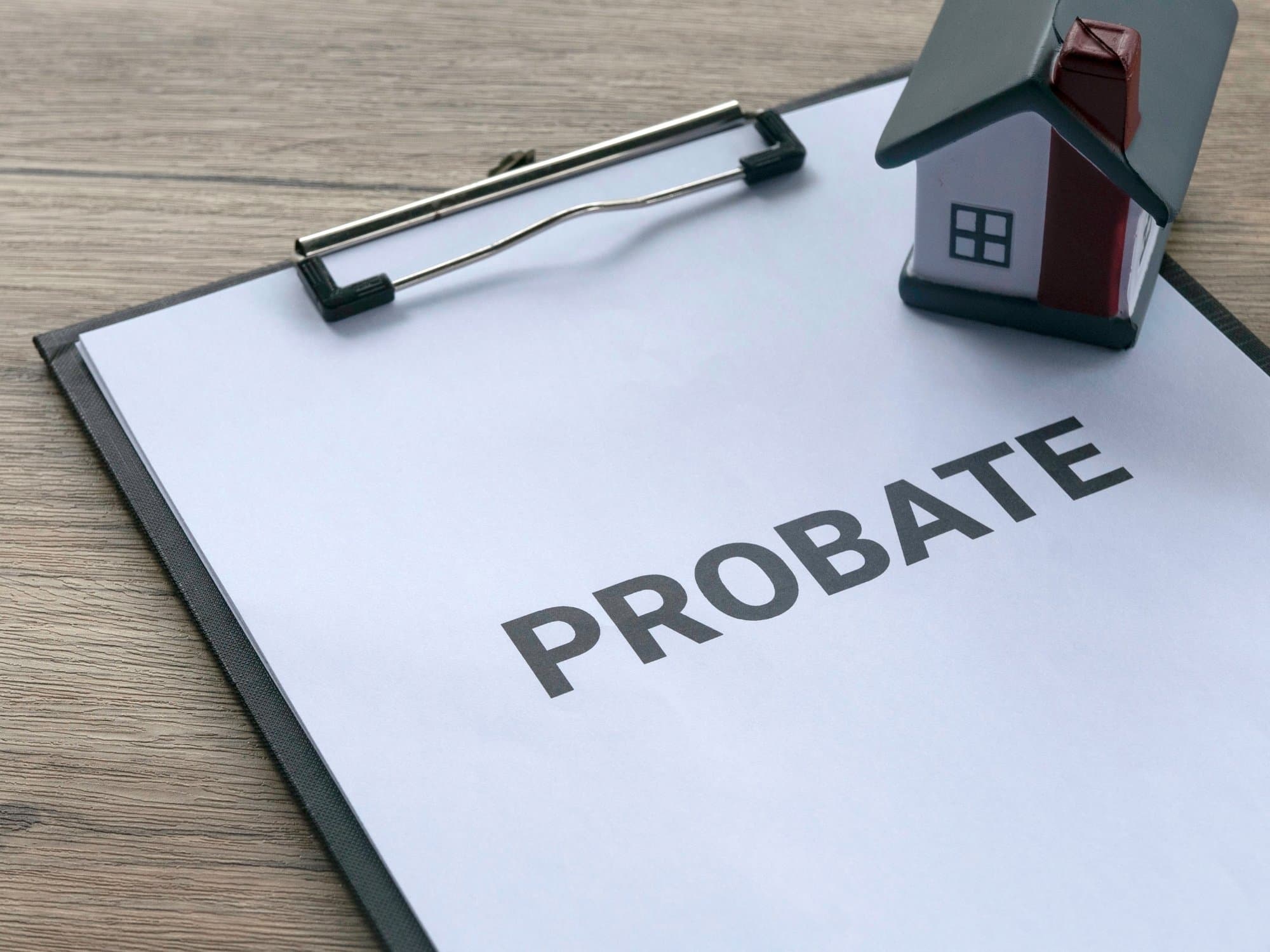 A probate document on a clipboard beside a model house