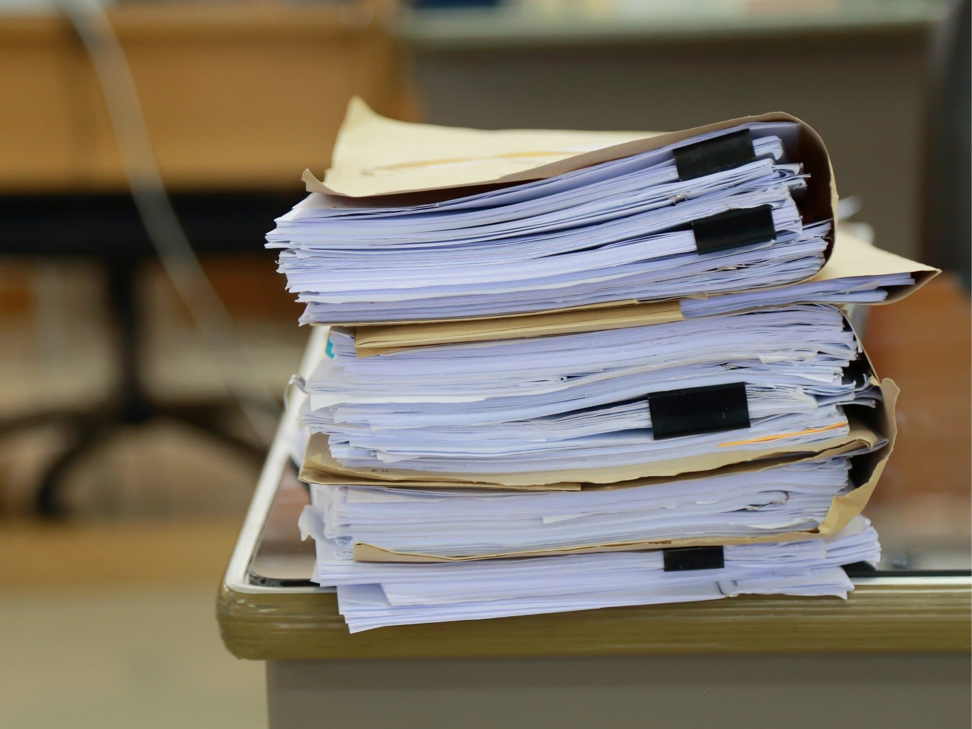 A stack of clipped case files and documents on a registry office desk